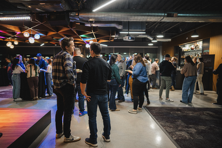people standing in crowded room with drinks and food